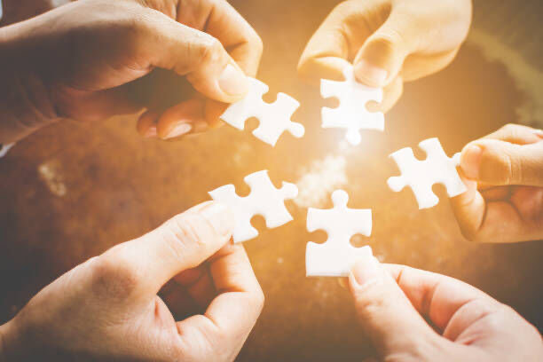 Close-up of hands fitting pieces of a puzzle together